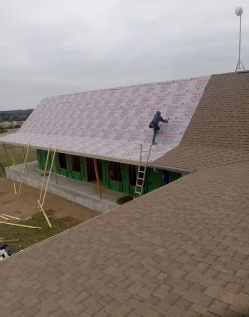 Worker preparing underlayment for a metal roof installation in Lake Hallie